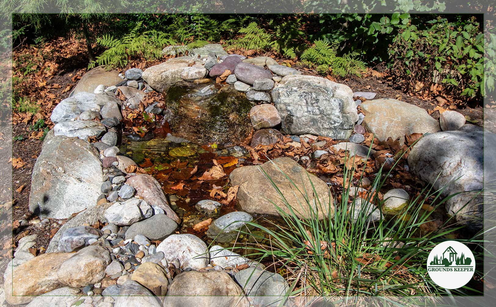 small fall pond with leaves surrounded by stone