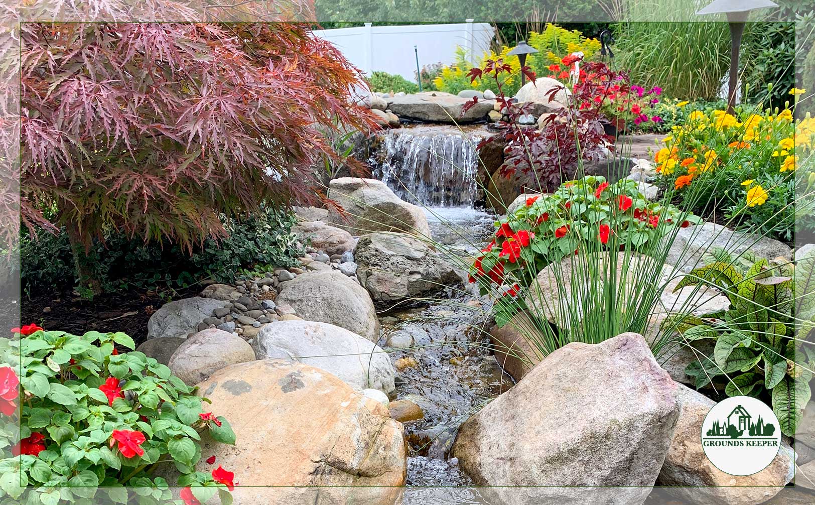 pond and waterfall with red and yellow summer flowers