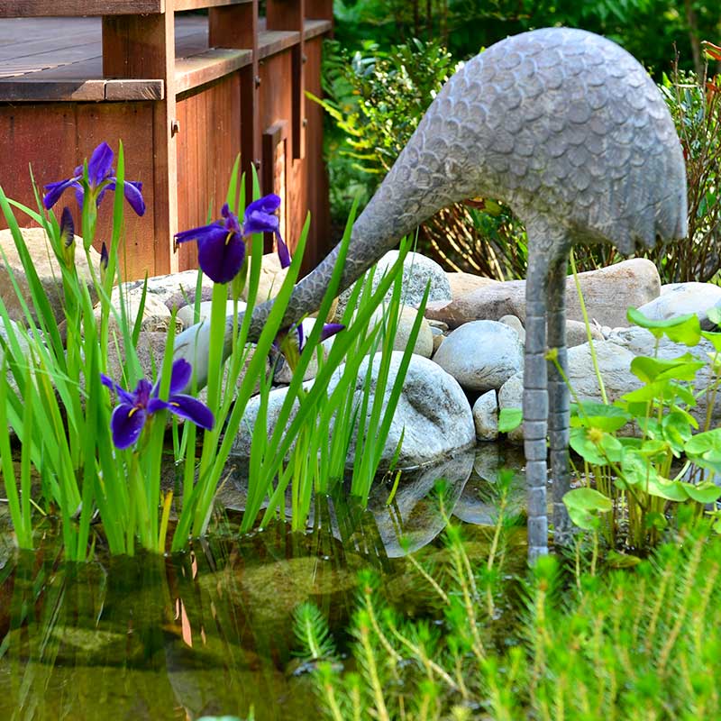 heron sculpture with purple flowers
